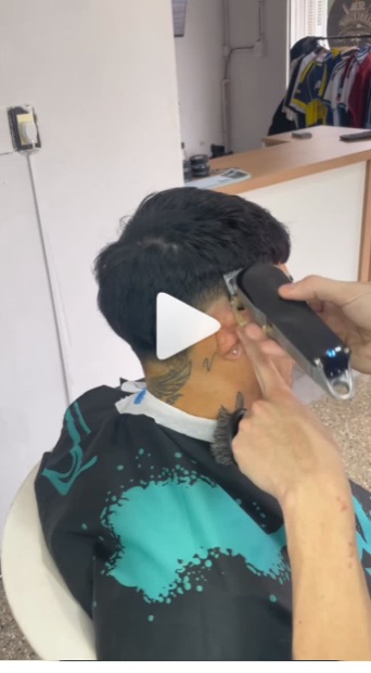 Perfilado de nuca y patilla con máquina, capa negra y turquesa.